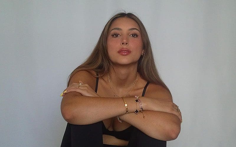 A woman with her arms crossed sitting on the ground.