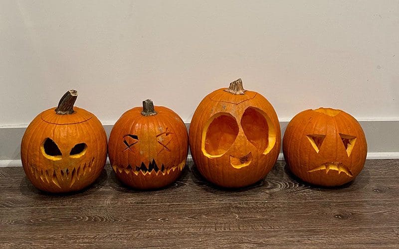 A row of pumpkins with faces drawn on them.