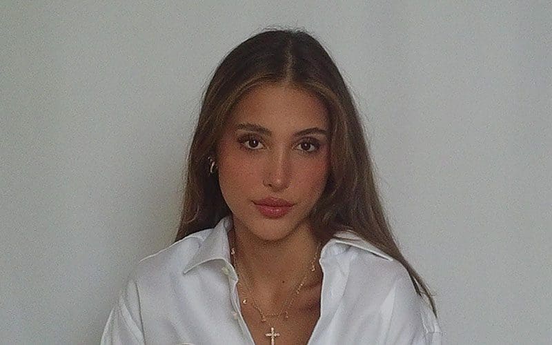 A woman in white shirt and necklace posing for the camera.