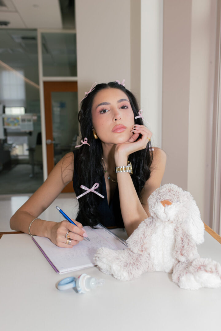 A woman sitting at a table with a stuffed animal.