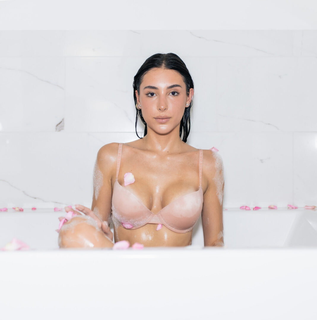 A woman in a pink bra sitting in the tub