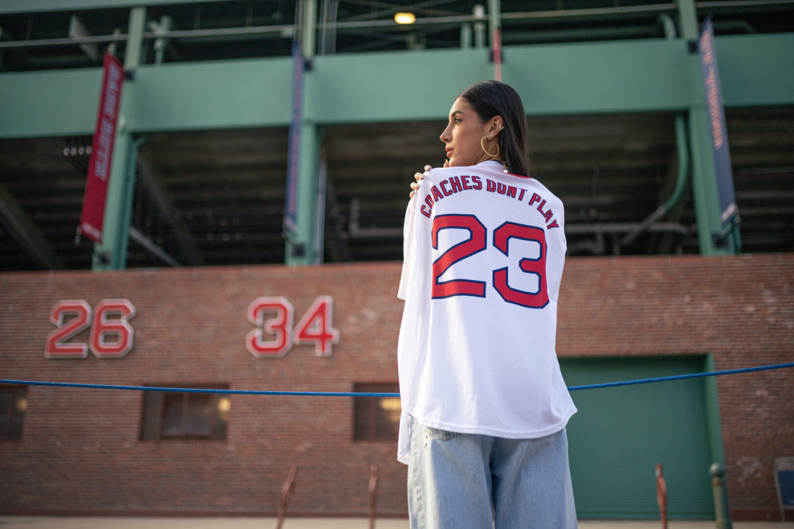 A woman in a baseball uniform standing on top of a field.