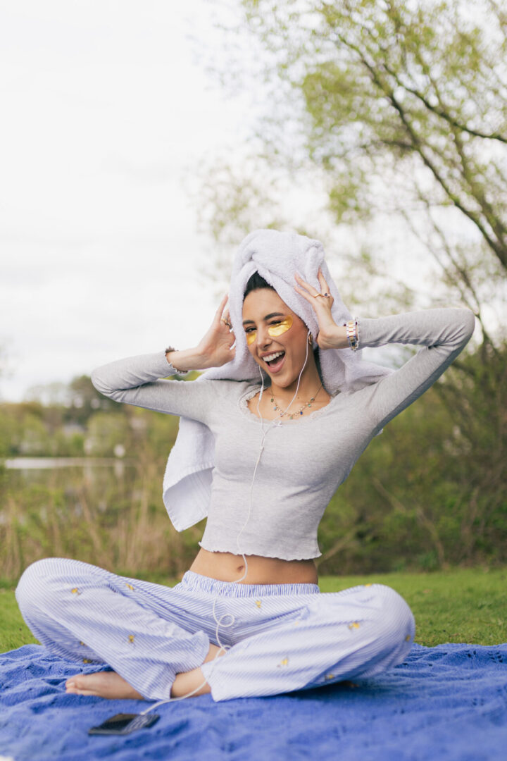 A woman in white shirt and pants sitting on grass.