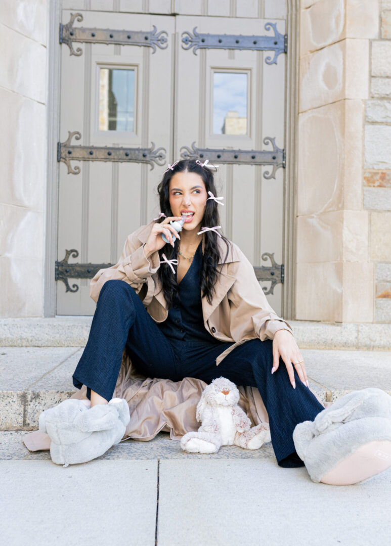 A woman sitting on steps with her teeth hanging out of her mouth.