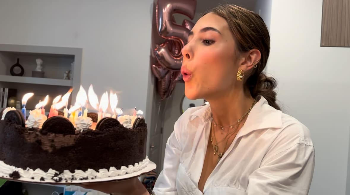 A woman blowing out candles on her birthday cake.